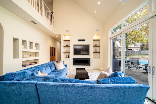 living room with built in features and high vaulted ceiling