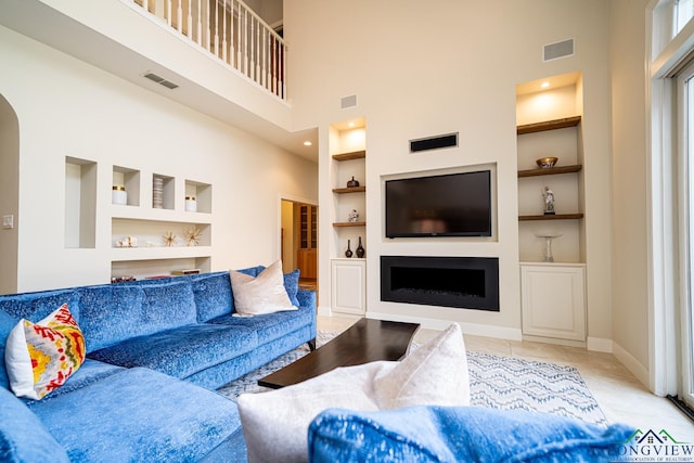 living room featuring built in shelves, a towering ceiling, and light tile patterned floors