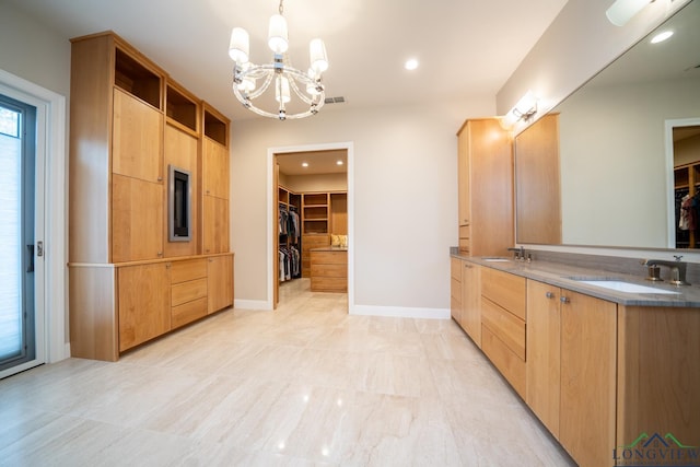 kitchen with light brown cabinetry, a chandelier, sink, and hanging light fixtures