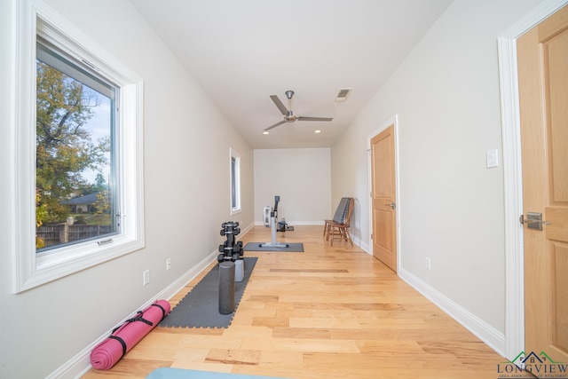 exercise room with ceiling fan and light wood-type flooring