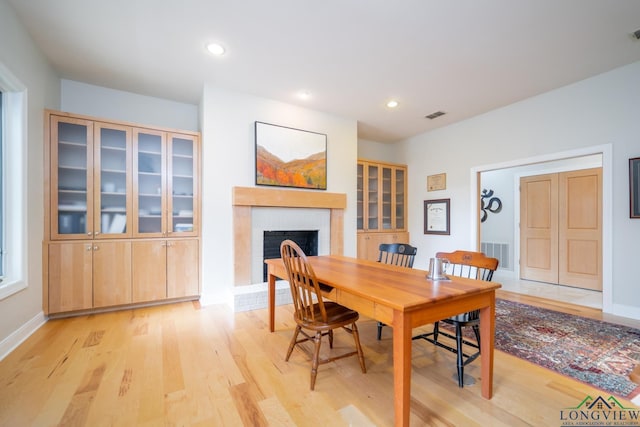 dining space featuring a fireplace and light wood-type flooring