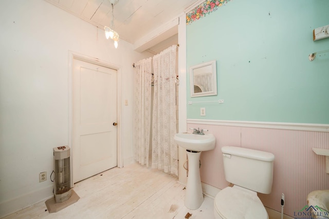 508 N Soda St, Jefferson, TX 75657 - bathroom featuring a wainscoted wall, toilet, curtained shower, a sink, and wood finished floors