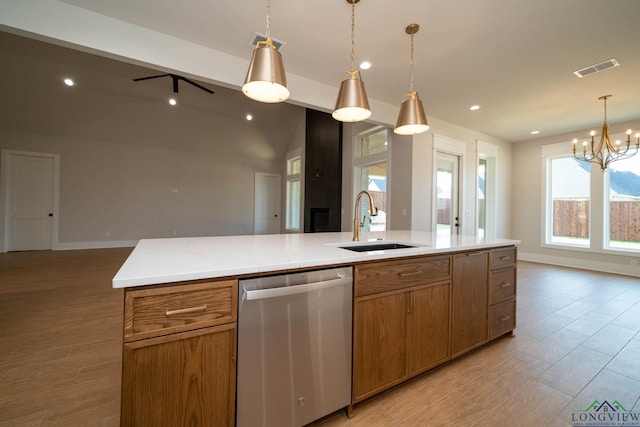 kitchen featuring a sink, open floor plan, a notable chandelier, brown cabinets, and dishwasher