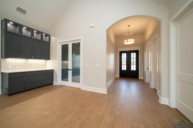 entrance foyer featuring french doors, arched walkways, light wood-type flooring, baseboards, and visible vents
