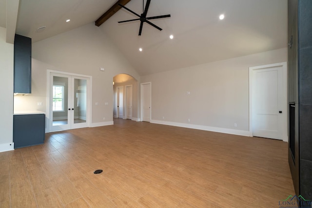 unfurnished living room featuring light wood finished floors, a ceiling fan, beamed ceiling, arched walkways, and high vaulted ceiling