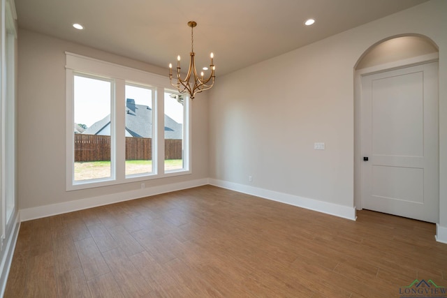 unfurnished room featuring baseboards, a notable chandelier, wood finished floors, and recessed lighting