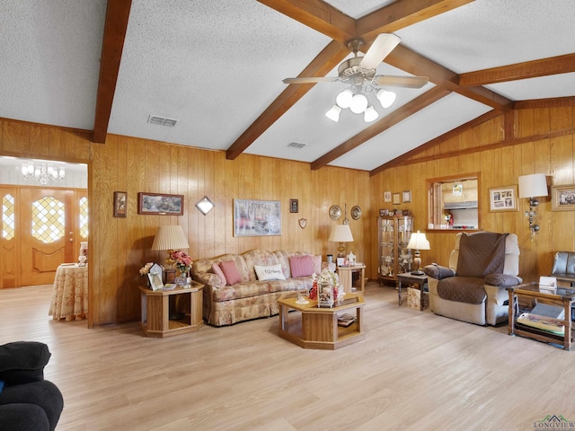 living area featuring vaulted ceiling with beams, wood finished floors, visible vents, and a textured ceiling