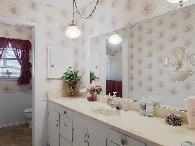 full bathroom with a wainscoted wall, toilet, a shower stall, wallpapered walls, and vanity