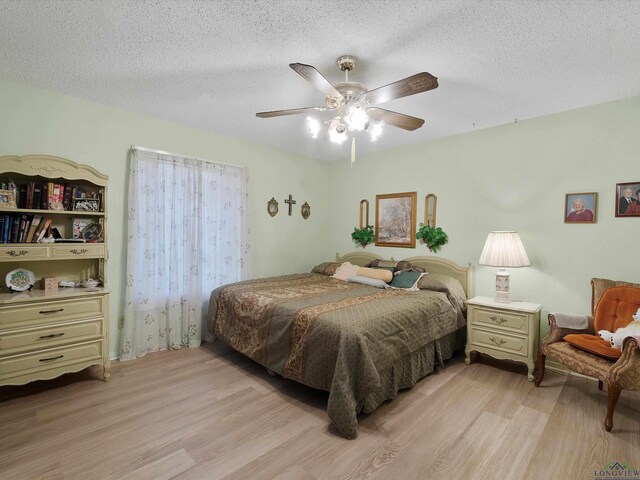 bedroom featuring light wood finished floors, a textured ceiling, and a ceiling fan