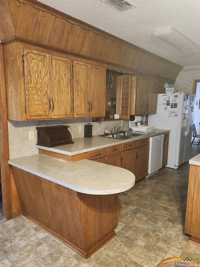 kitchen with a sink, white appliances, a peninsula, and light countertops