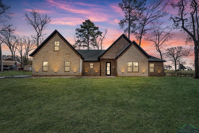 french country inspired facade featuring brick siding and a front yard