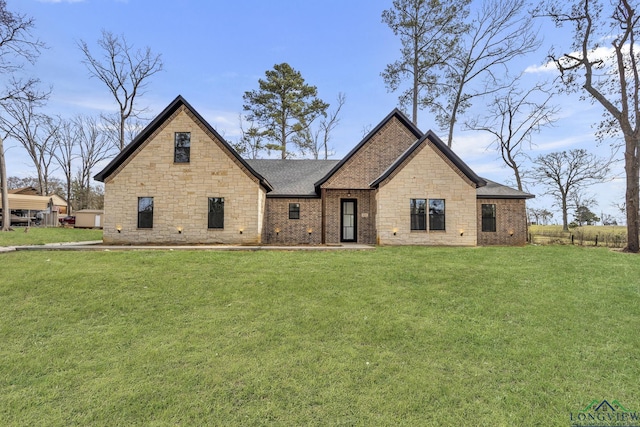 view of front of house with a shingled roof, a front yard, and brick siding