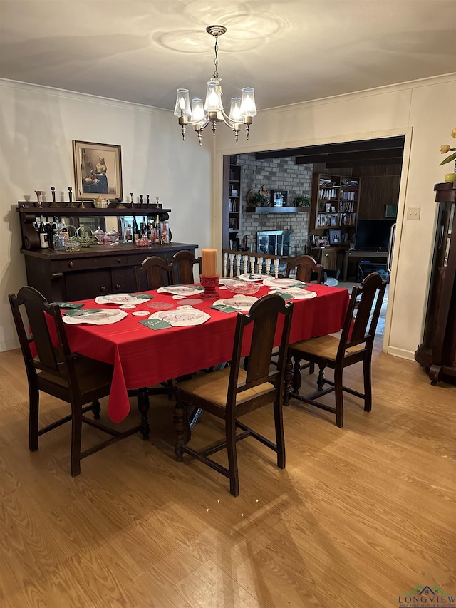 dining space with a brick fireplace, light hardwood / wood-style flooring, and an inviting chandelier