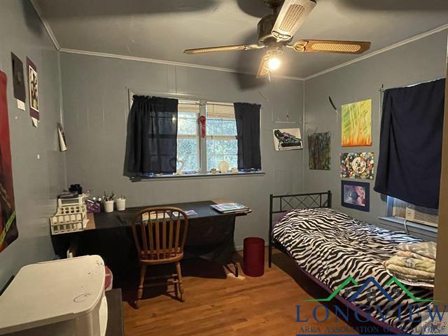 bedroom with hardwood / wood-style flooring, ceiling fan, and ornamental molding