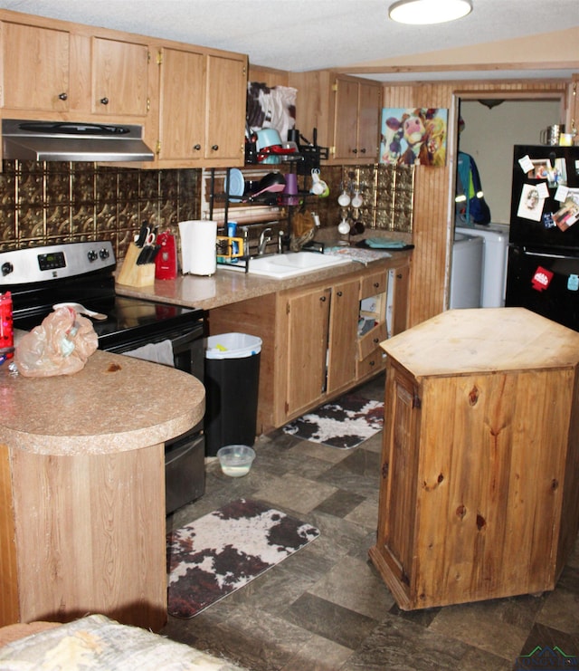 kitchen with washer / dryer, light countertops, a sink, and under cabinet range hood