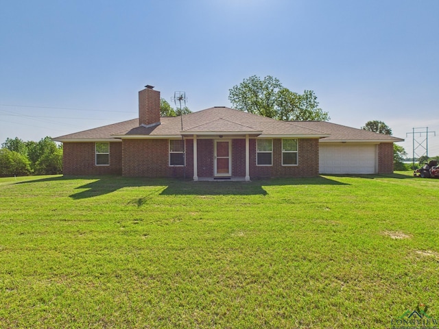 rear view of house featuring an attached garage, a chimney, brick siding, and a lawn