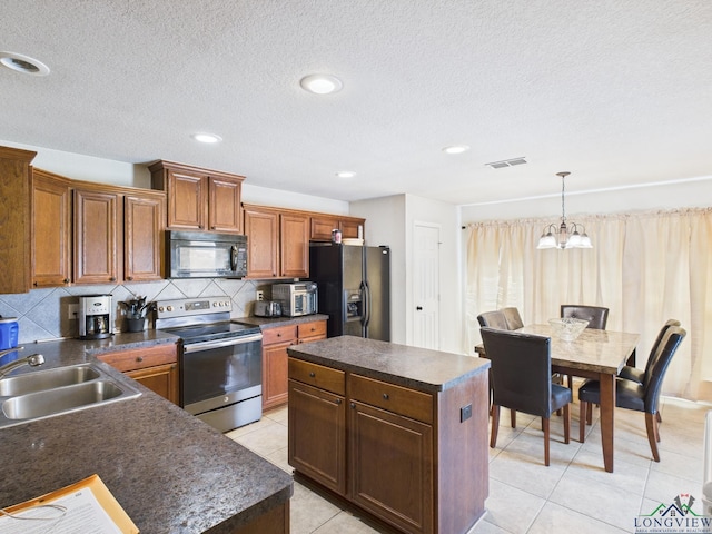 kitchen with light tile patterned floors, visible vents, a sink, dark countertops, and black appliances