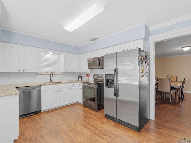 kitchen featuring sink, stainless steel appliances, crown molding, light hardwood / wood-style floors, and white cabinets