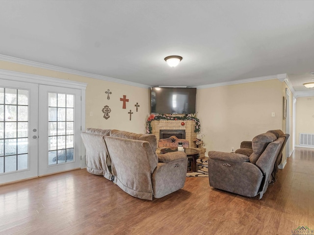 living room featuring hardwood / wood-style flooring, ornamental molding, a fireplace, and french doors