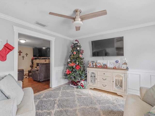 living room with a fireplace, light tile patterned floors, ceiling fan, and crown molding