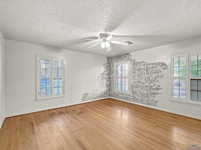 unfurnished room featuring wood finished floors, a textured ceiling, ceiling fan, and a healthy amount of sunlight