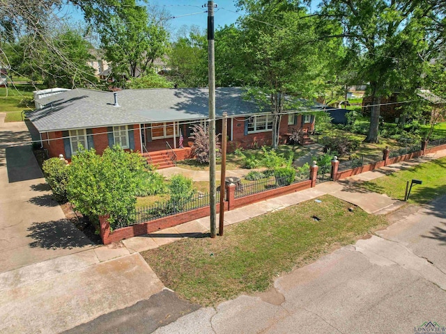 single story home with a porch, a shingled roof, brick siding, and a fenced front yard
