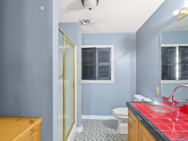 bathroom with visible vents, toilet, vanity, a textured ceiling, and a stall shower