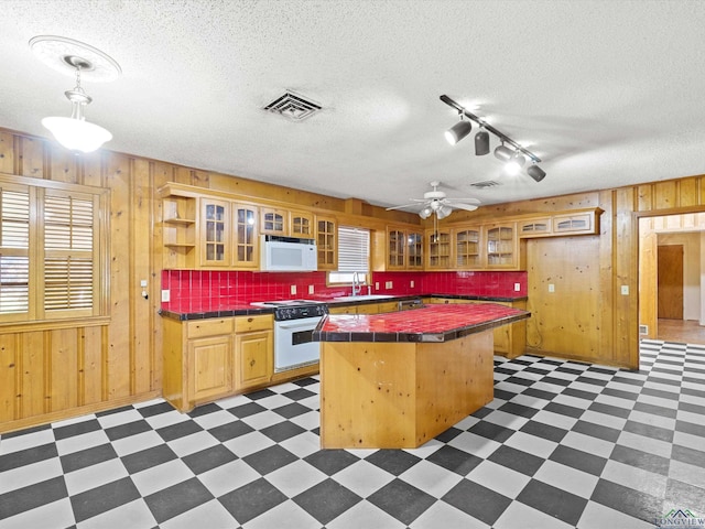 kitchen with tile counters, a sink, white appliances, wooden walls, and rail lighting