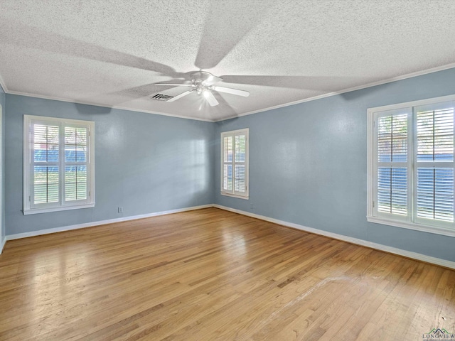 spare room with wood finished floors, visible vents, a ceiling fan, ornamental molding, and a textured ceiling