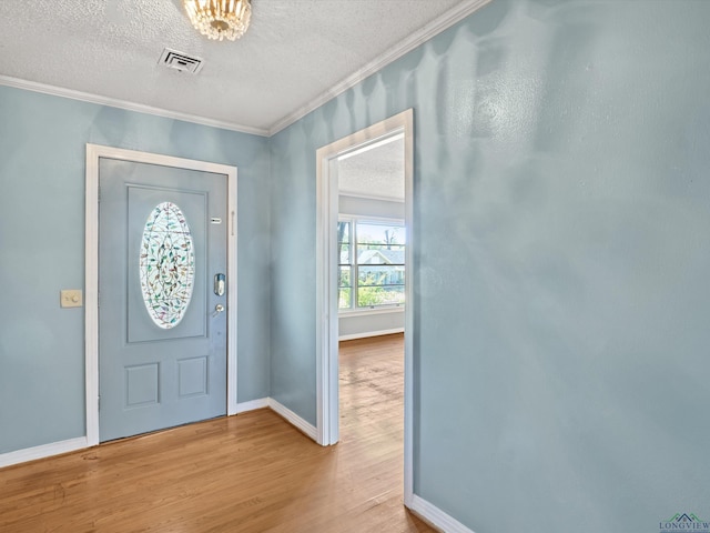 entrance foyer with wood finished floors, visible vents, crown molding, baseboards, and a textured ceiling
