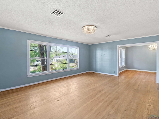 spare room with a healthy amount of sunlight, a chandelier, and visible vents