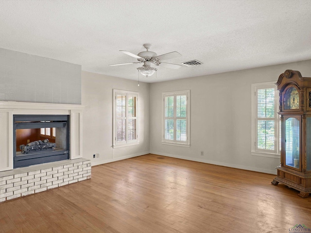 unfurnished living room with ceiling fan, wood finished floors, visible vents, and a textured ceiling