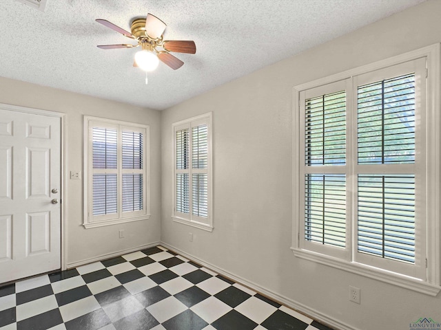foyer featuring tile patterned floors, baseboards, a textured ceiling, and ceiling fan