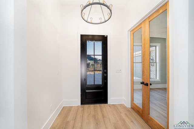 doorway with plenty of natural light, a chandelier, and light hardwood / wood-style floors