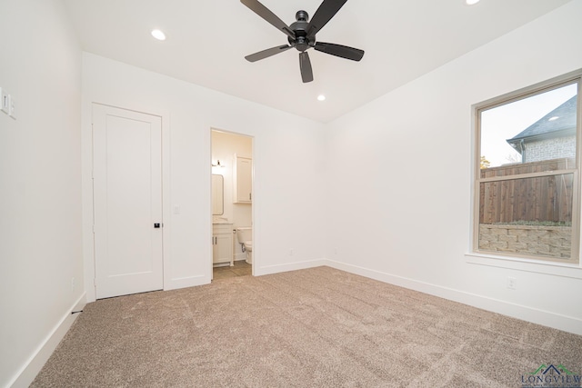 unfurnished bedroom featuring ceiling fan, connected bathroom, and light colored carpet