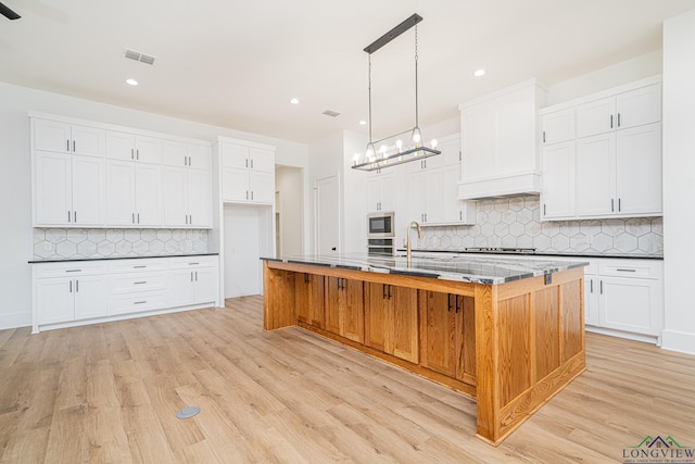 kitchen featuring white cabinetry, appliances with stainless steel finishes, and an island with sink