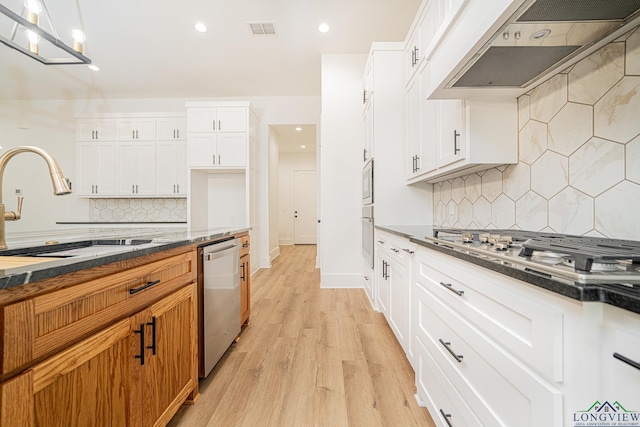 kitchen featuring stainless steel appliances, custom exhaust hood, and white cabinets