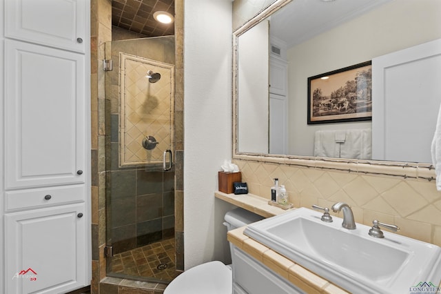 bathroom featuring vanity, a shower with door, backsplash, toilet, and ornamental molding