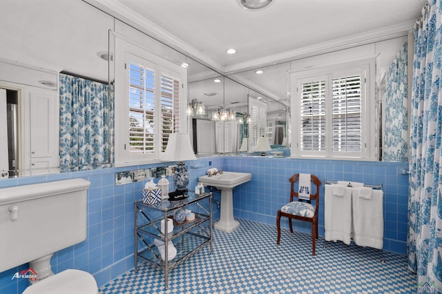 bathroom with toilet, a healthy amount of sunlight, crown molding, and tile walls