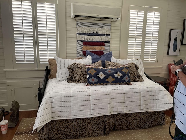 bedroom featuring wood-type flooring and an AC wall unit