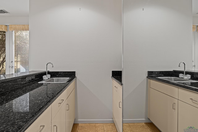 kitchen with cream cabinets, dark stone counters, and sink