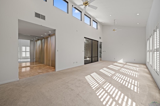 unfurnished living room with light carpet, ceiling fan, and a high ceiling