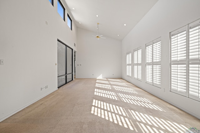 spare room featuring ceiling fan, light carpet, and high vaulted ceiling