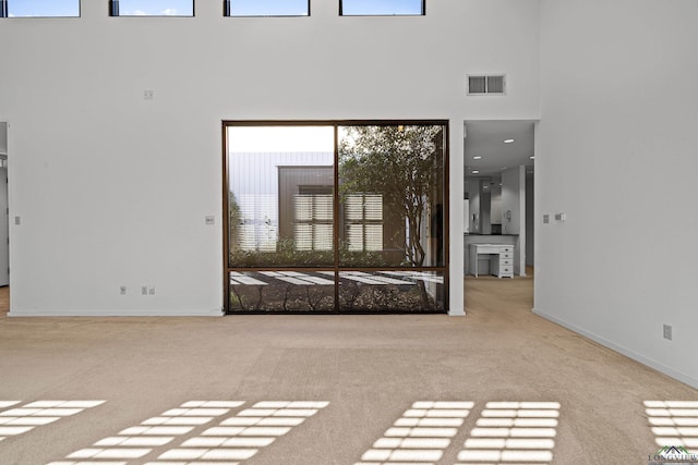 interior space featuring a towering ceiling and light colored carpet