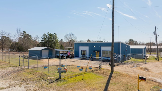 exterior space with fence, a pole building, a detached garage, and an outbuilding