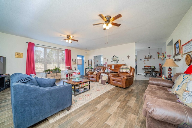 living room featuring a ceiling fan, a textured ceiling, and wood finished floors