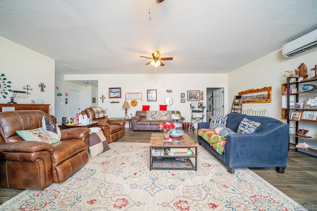 living room with ceiling fan, an AC wall unit, a textured ceiling, and wood finished floors