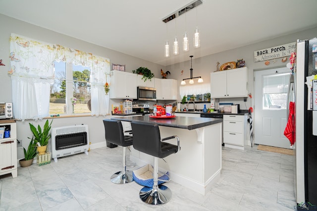 kitchen featuring dishwashing machine, heating unit, dark countertops, stainless steel microwave, and a kitchen bar