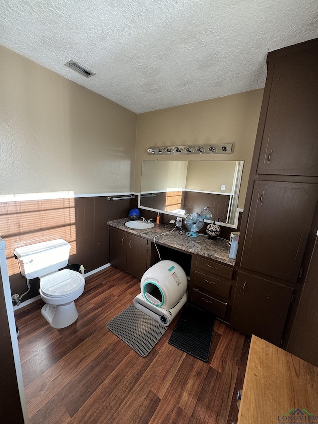 bathroom with hardwood / wood-style flooring, vanity, toilet, and a textured ceiling