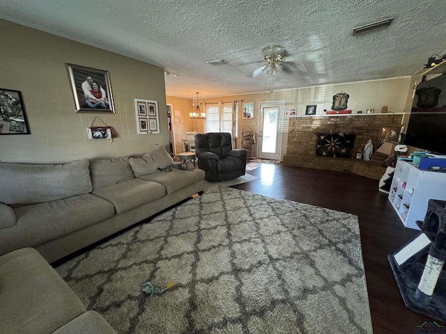 living room with a textured ceiling, ceiling fan with notable chandelier, a fireplace, and dark wood-type flooring